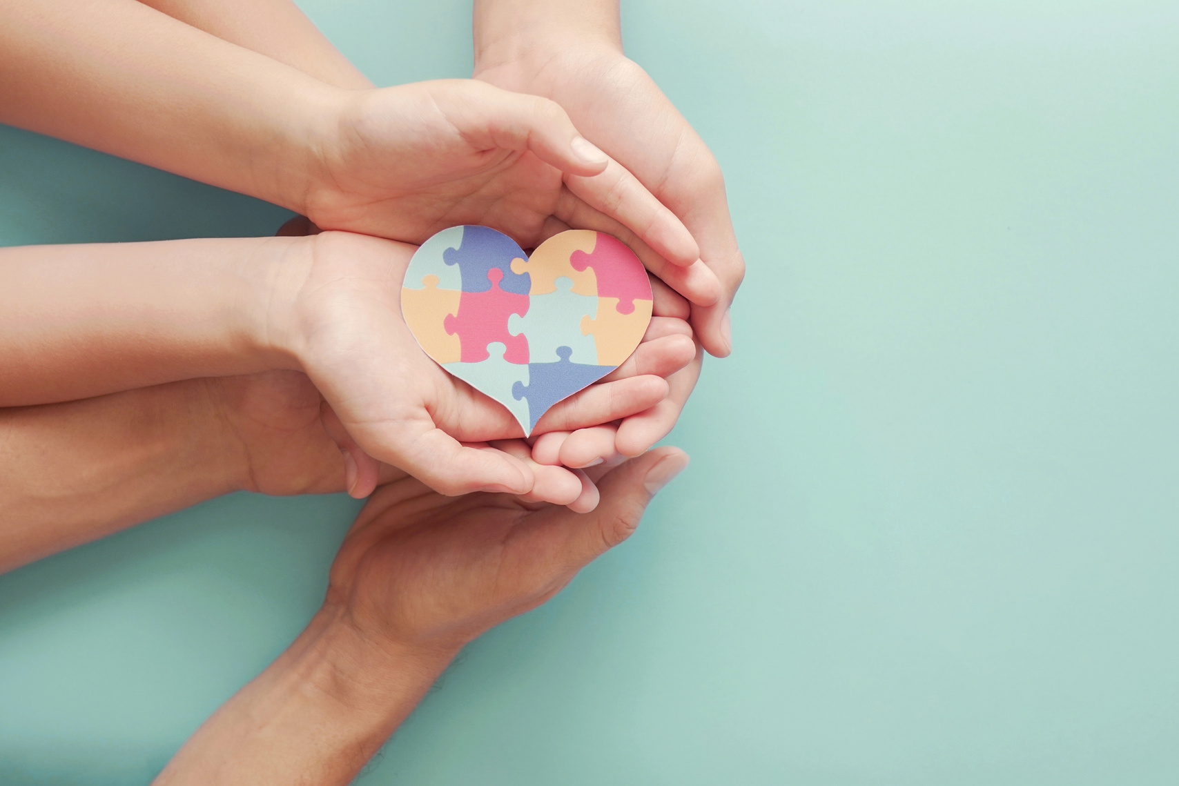 Adult and chiildren hands holding jigsaw puzzle heart shape, Autism awareness,Autism spectrum disorder family support concept, World Autism Awareness Day
